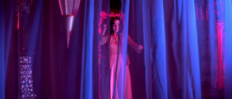 Suzy looks in fear through a curtain where Helena Markos rests