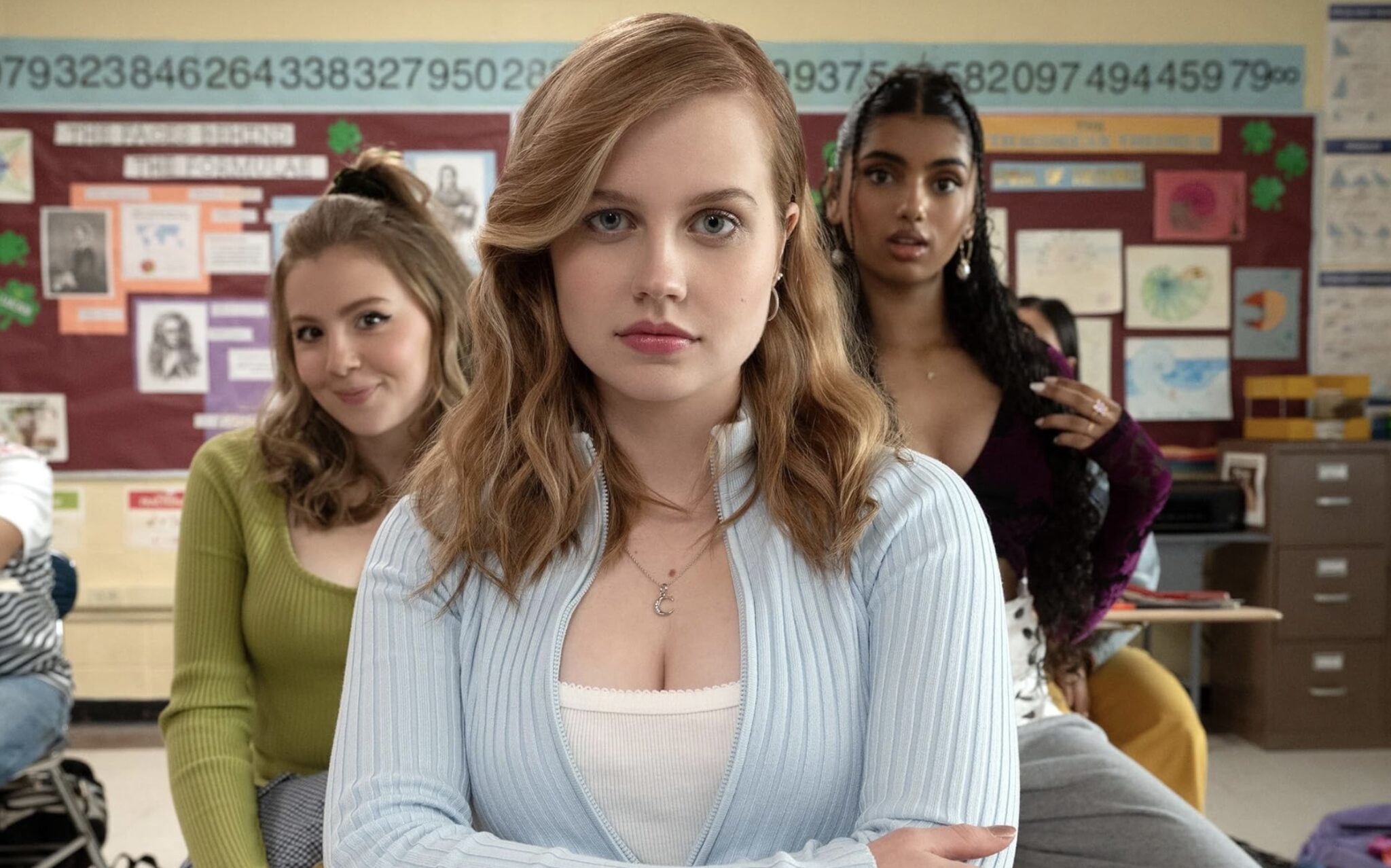 Three high school girls, in school, look at the camera.