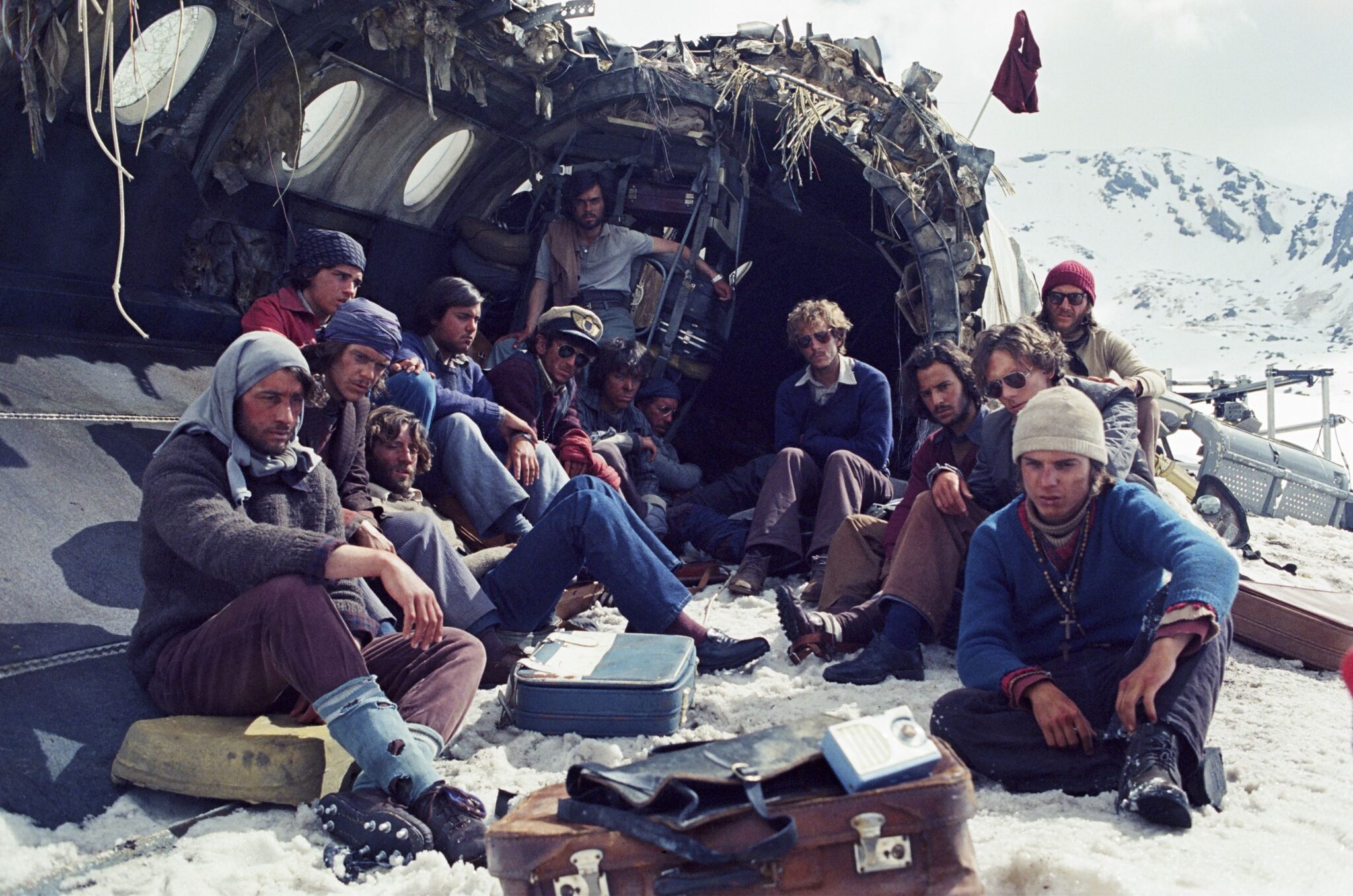 A group of young men sit in the wreckage of an aircraft in the middle of winter.