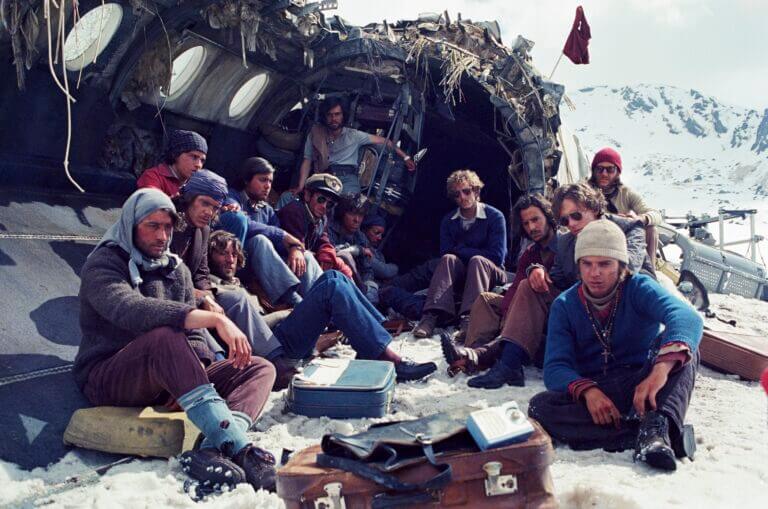 A group of young men sit in the wreckage of an aircraft in the middle of winter.