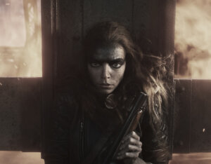 Furiosa stands in front of a fireball