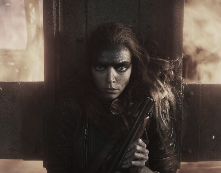 Furiosa stands in front of a fireball
