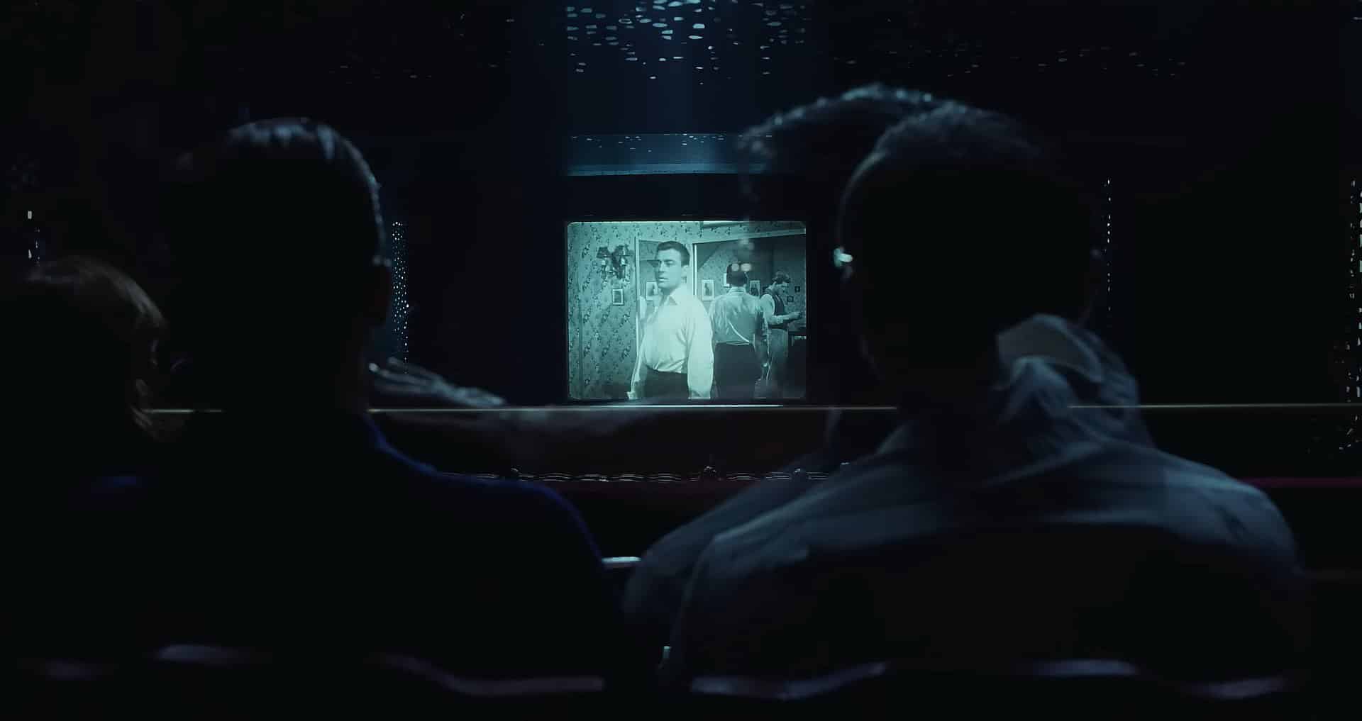 Two men watch a movie in a theater