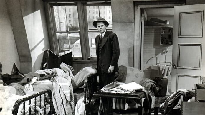 Frank (Glenn Ford) looks around his room, which has been trashed and raided through