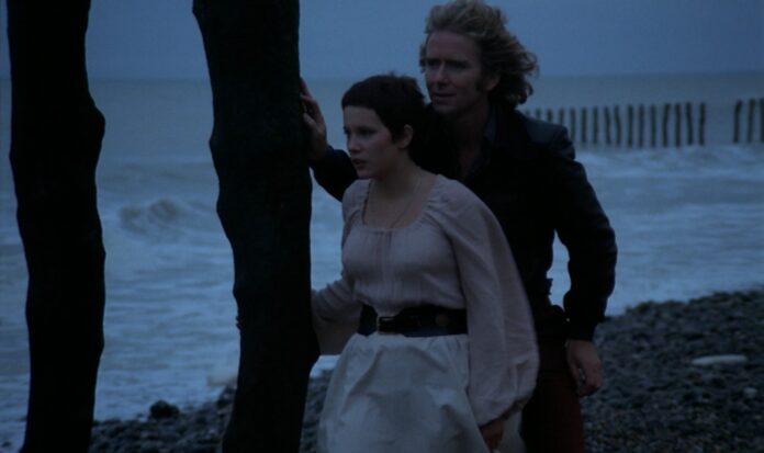 Frédéric and Jennifer stand on a shore of a beach