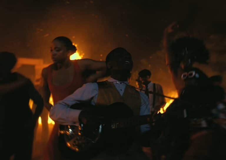 Sammy plays guitar in front of a fire
