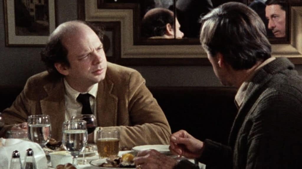 a man in a suit and tie talking to another man